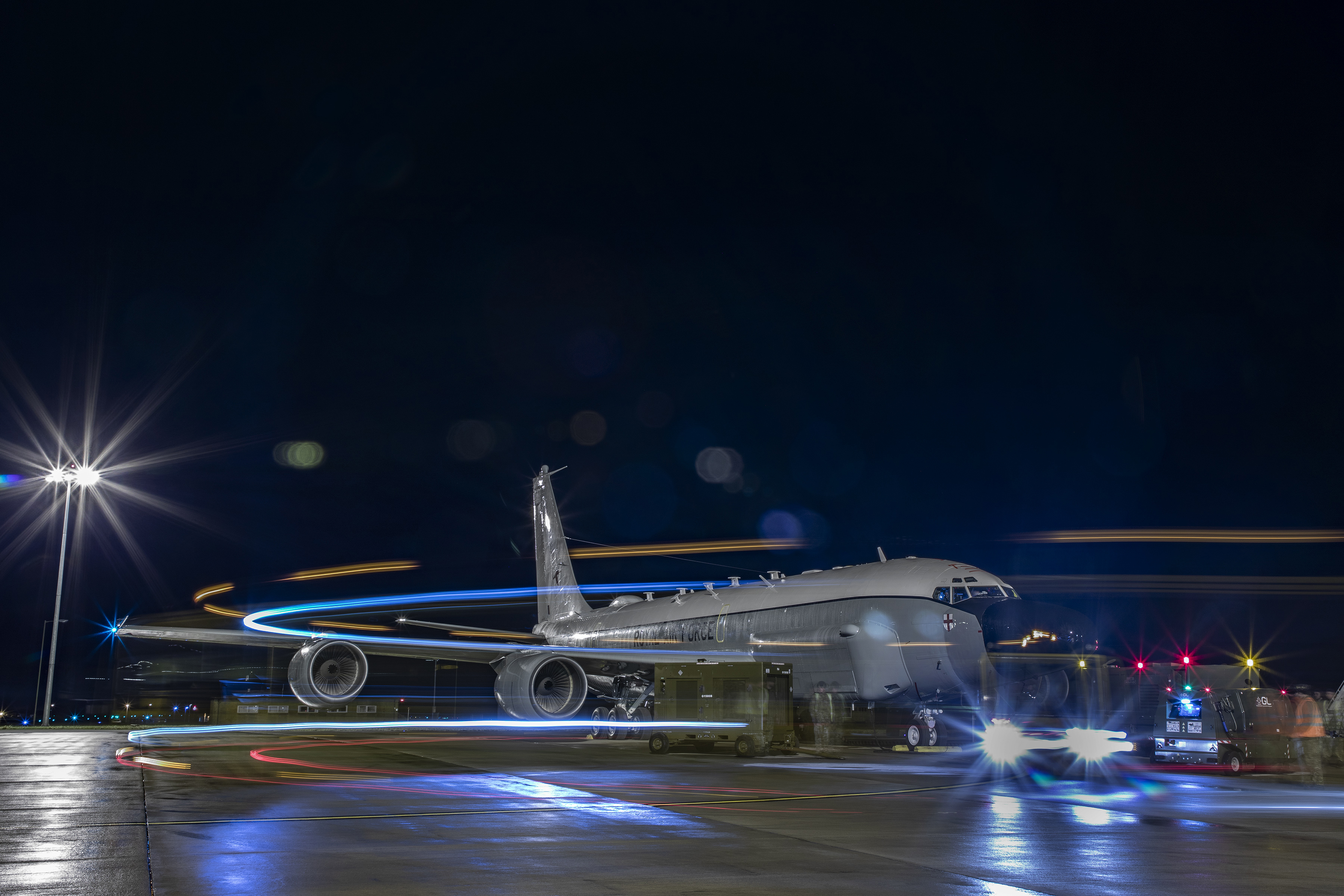 Rivet Joint carrier aircraft on the runway at night, with lights on. 
